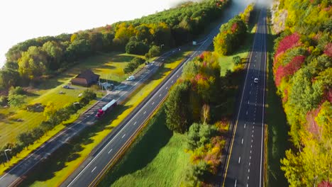 Aerial-of-a-car-traveling-on-a-highway-through-the-fog-in-fall