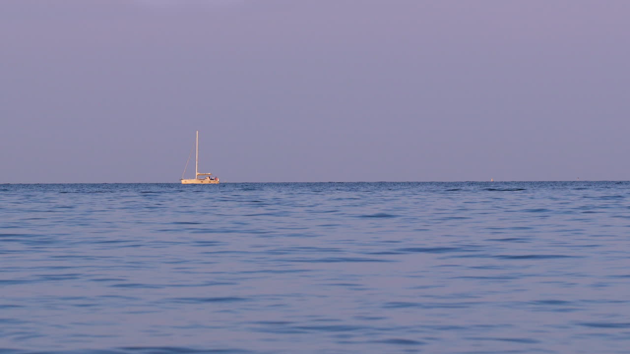 Wide seascape at golden hour with a lone sailboat on the horizon under pastel violet sky; tranquil maritime panorama