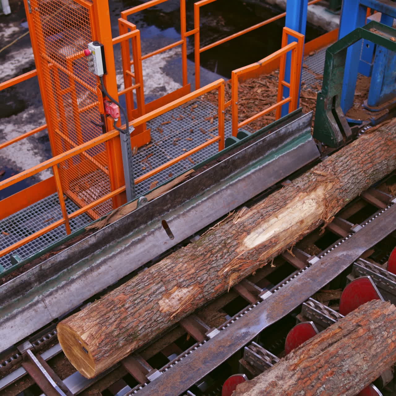 Sawmill. Process of machining logs in a machine. Wood industry. Top view on machinery. Heavy technic closeup.