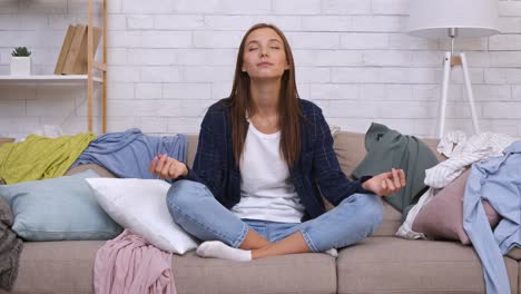 mujer meditando en un sofá desordenado