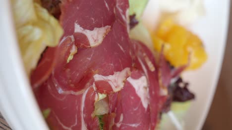 close-up of cured meat and green salad