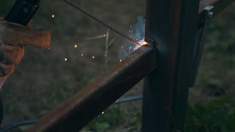 slow-motion-closeup-handyman-welds-fence-part-to-support