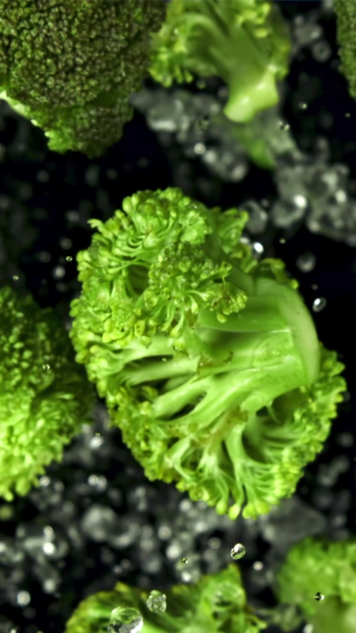 Cimette di broccoli freschi e verdi che schizzano nell'acqua al rallentatore