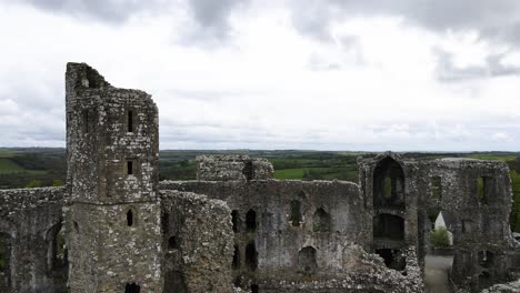 aerial forward over llawhaden castle ruins surrounded by green welsh countryside, uk