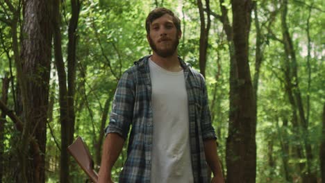 proud caucasian north american male standing in the forest with shotgun in his hand looking straight at the camera