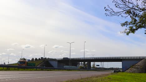 time lapse or timelapse footage of pärnu highway and a bridge over and underpass during summer time when its slightly cloudy and sunny. cars and vehicles driving, speeding on the road with markings.