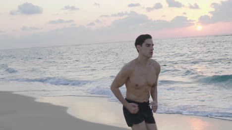 athletic young runner jogging alone on beach in the evening