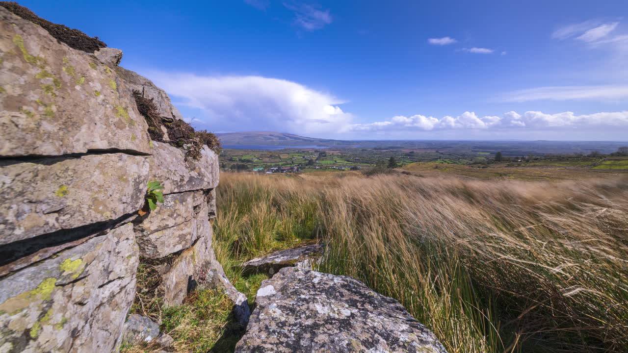 Time lapse of rural landscape with rocky foreground and hills and lake in the distance with passing storm showers during a spring day in Arigna mountains in county Leitrim in Ireland