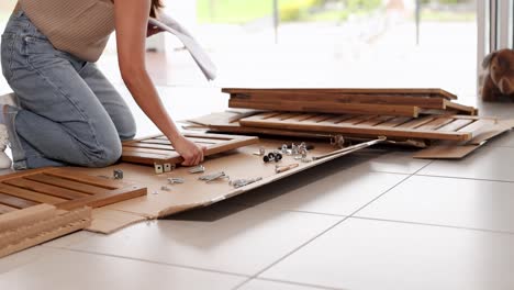 person organizing wooden panels and hardware on a tiled floor in bright natural light