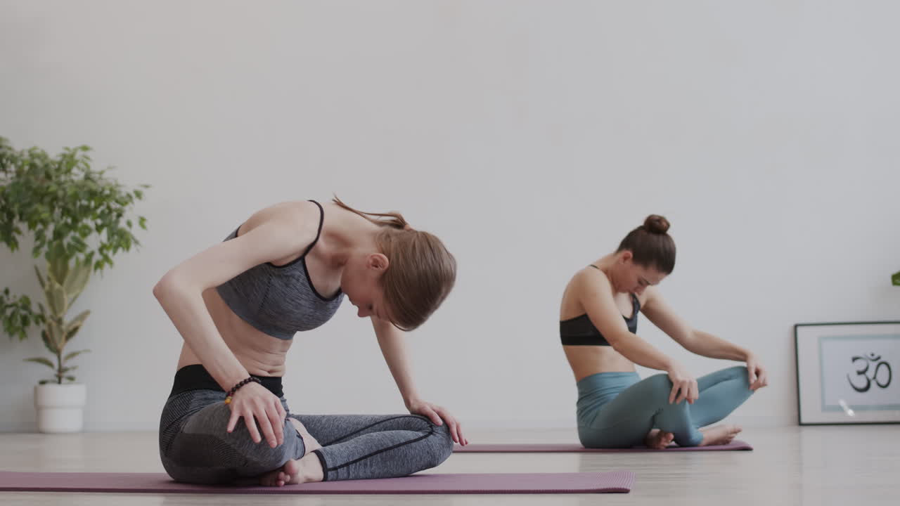 dos mujeres caucásicas deportivas estirándose juntas.