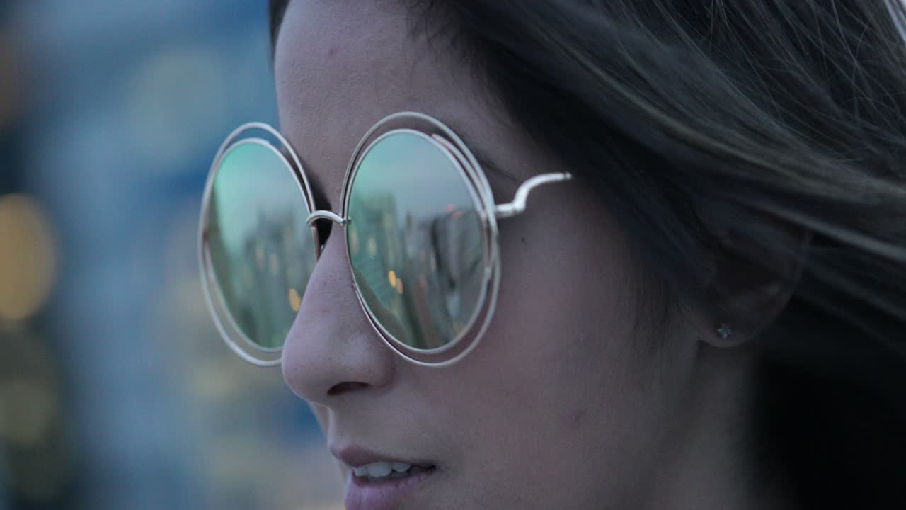 chica posando con gafas de sol grandes y redondas por la noche