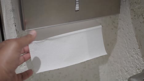 hand taking paper towel from dispenser