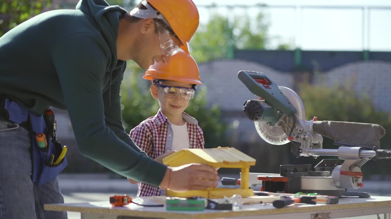el padre y el hijo haciendo un alimentador de madera juntos. cámara lenta