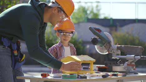 the father and son making a wooden feeder together. slow motion