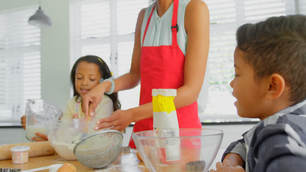 madre negra con sus hijos preparando comida en la cocina en casa 4k