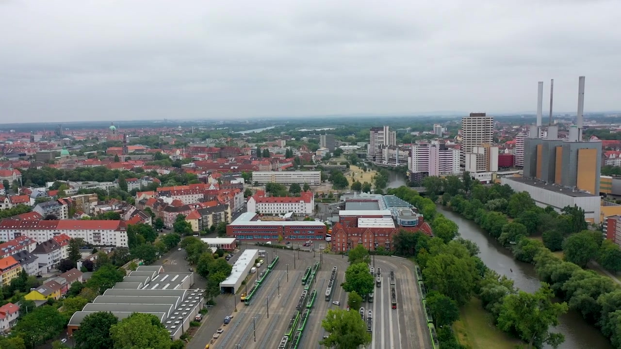Rozległy widok z lotu ptaka na Hanower w Niemczech, prezentujący krajobraz miejski, zajezdnię tramwajową oraz otaczającą rzekę i tereny zielone.