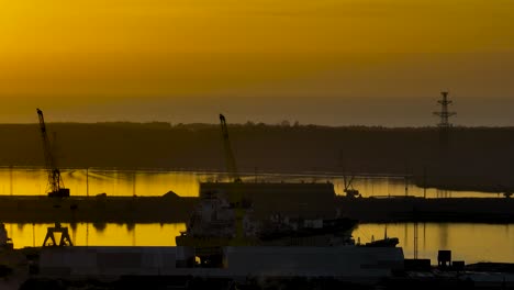 A-beautiful-view-of-the-silhouettes-of-cranes-and-buildings-standing-in-the-port-area-on-a-calm,-sunny-evening