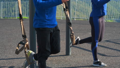 couple working out outdoors with suspension training equipment