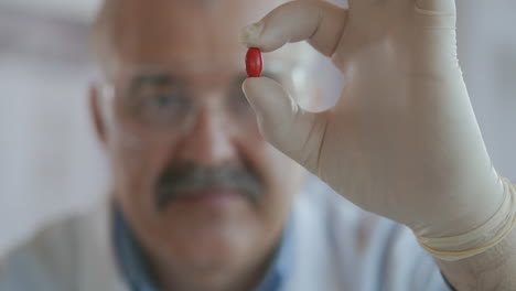 a male scientist holds a red pill in his hands and looks at it close up slow motion. high quality 4k footage