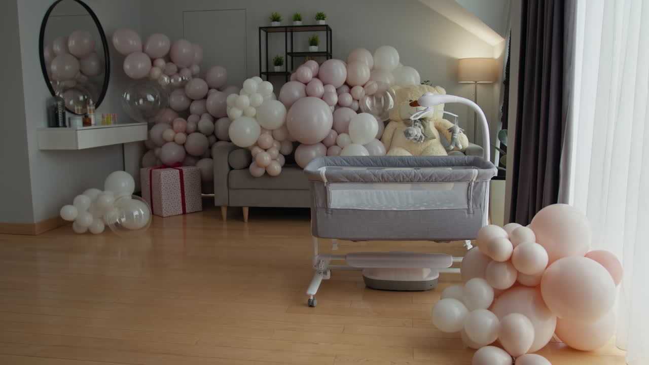 Elegante cameretta per neonati con raffinate decorazioni a palloncino in colori tenui e culla pronta per il neonato.