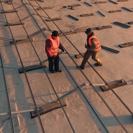 solar technicians on a rooftop. metal base for future photovoltaic panels of a solar farm on a roof a building. aerial view.