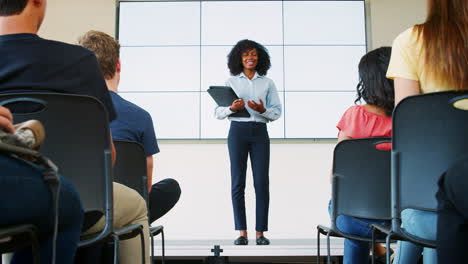 high school students applaud female teacher giving presentation in front of screen