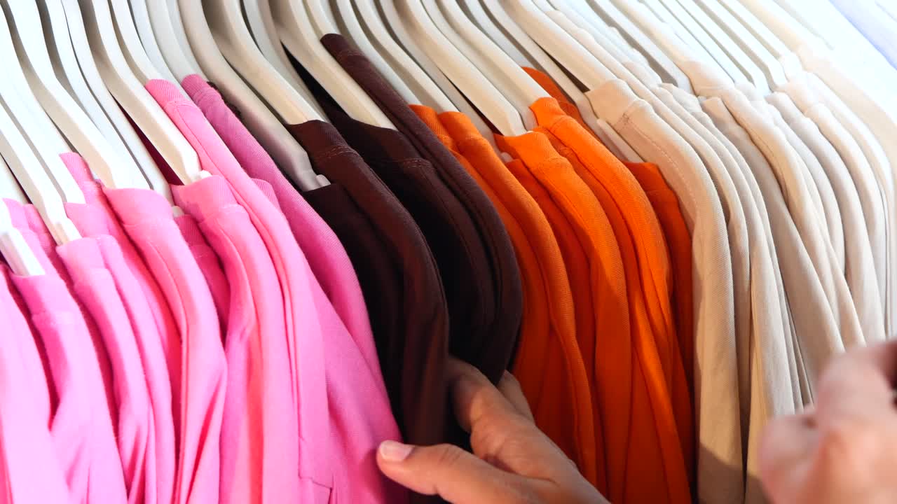 Person Choosing T-shirts from Rack