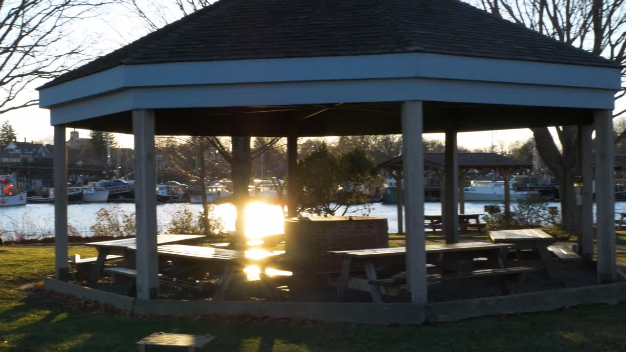 A slider shot of a gazebo, on a pier, as the sun sets in over the ocean.