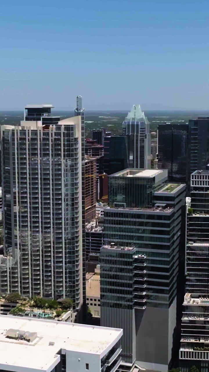 Imagem vertical de drone ao redor de um arranha-céu no centro de Austin, Texas ensolarado, EUA.