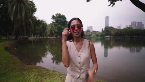 woman in park with heart sunglasses and headphones