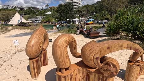 wooden sculptures displayed on sandy beach