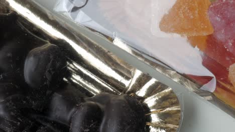 smooth pan right showing glossy dark chocolate-coated almonds on an elegant golden tray