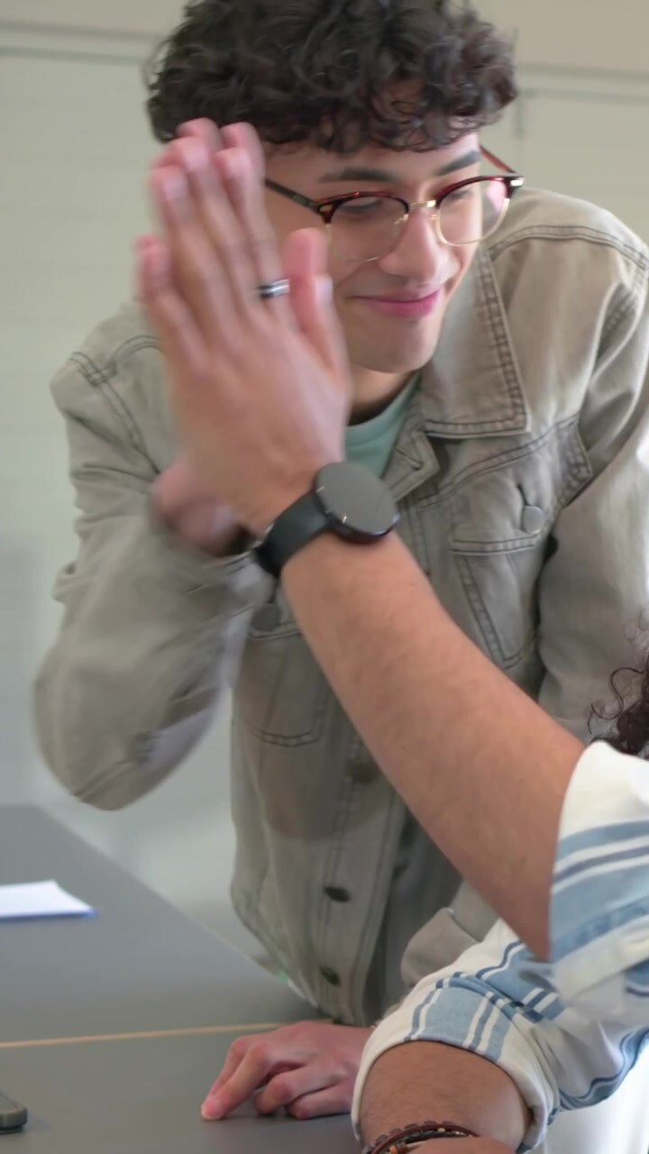 Vertical video: Leaning man with glasses reviewing project on laptop at study table, clapping