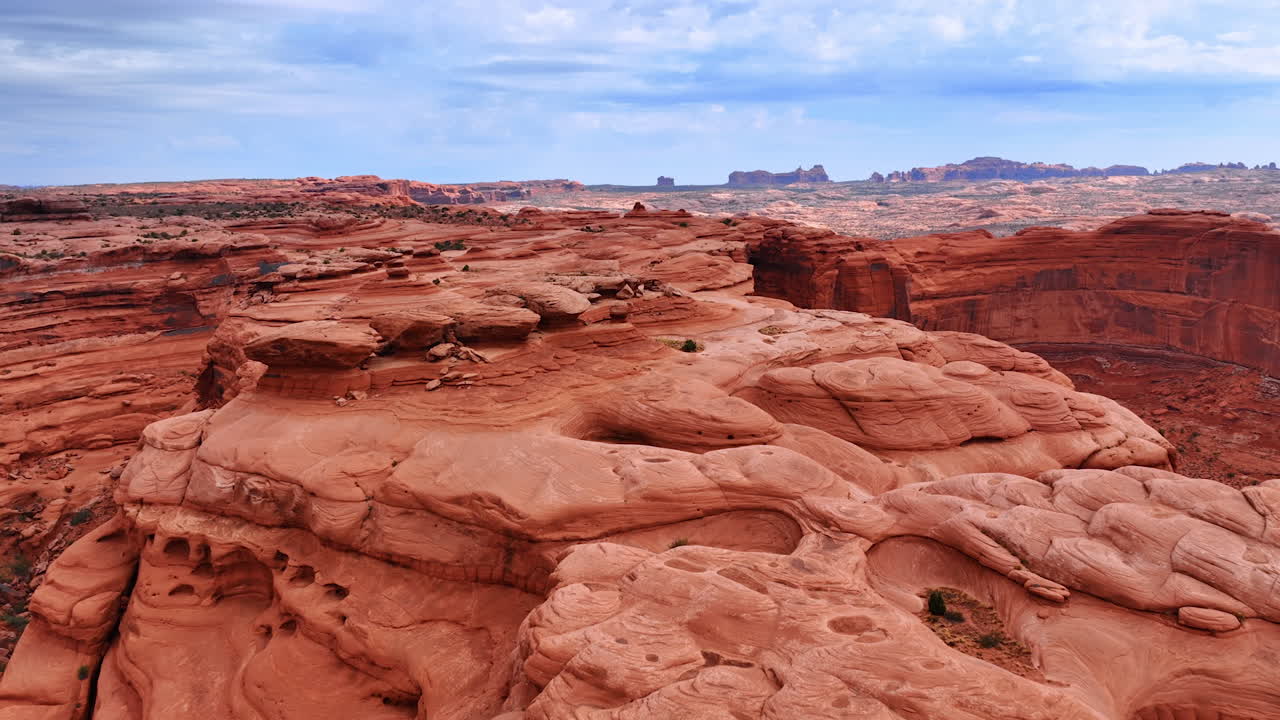 Parco nazionale degli Arches, Red Rock Canyon con scogliere stratificate e paesaggio desertico. Formazioni di arenaria illuminate dal sole sotto un cielo parzialmente nuvoloso mostrano meraviglie geologiche naturali