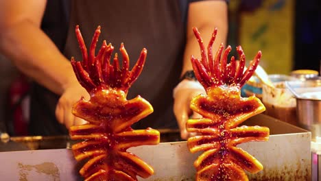 vendor grilling squid skewers at a food stall