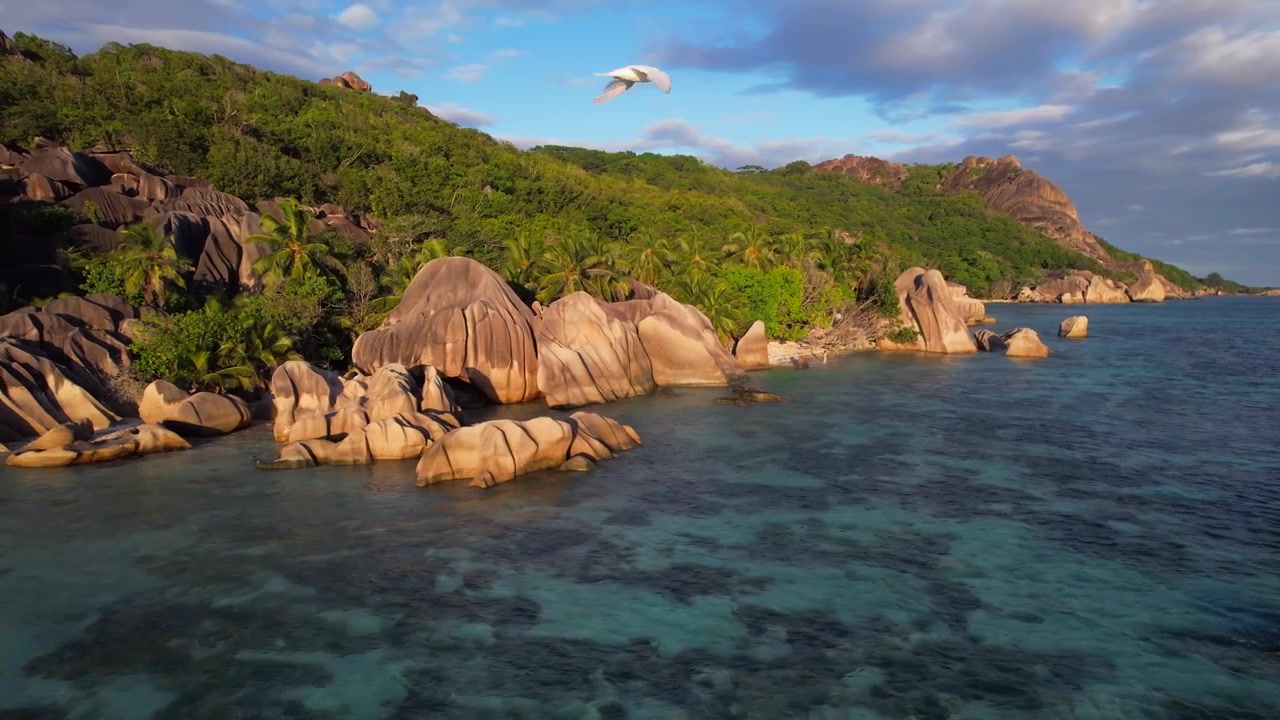 Massi di granito costeggiano la costa di La Digue nella calda luce del tramonto. Vista aerea.