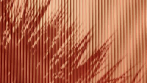 shadow of tree branches and leaves on vertical orange corrugated metal wall. abstract natural light and linear pattern background. design for wallpaper, banner, postcard, greeting card, header.