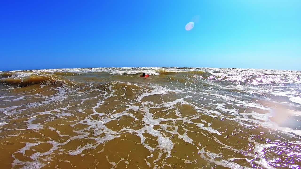 Dirty water with foamy waves in the sea. Child swimming in not clean sea water in summer time.