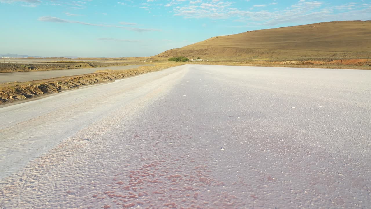 Aerial View of White Salt Field by Road and Great Salt Lakes Landscape in Utah USA On Sunny Summer Day