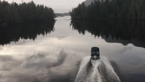 a power boat driving on glassy water on vancouver island, british columbia