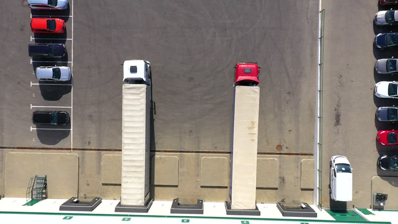 화물 트레일러가 있는 세미 트럭이 물류 공원의 창고를 따라 주차장을 이동하고 있습니다.