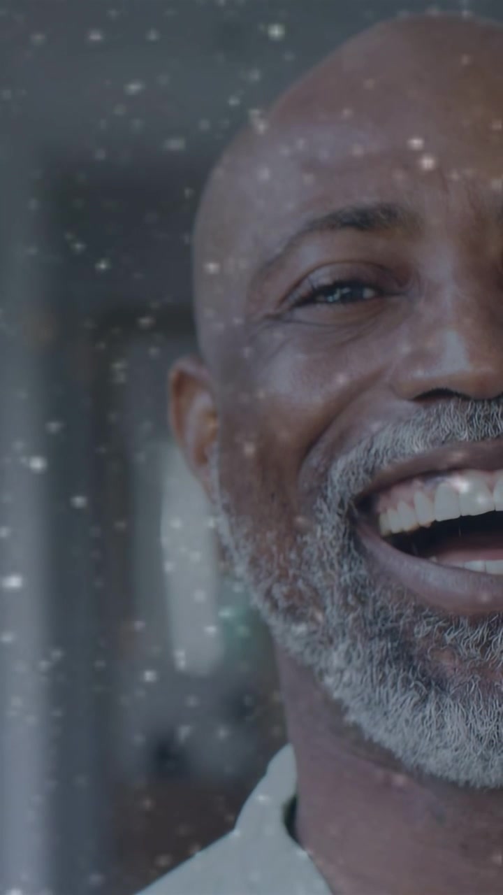 Vertical video: Man smiling then laughing after glass overlay band and dust appearing for marketing