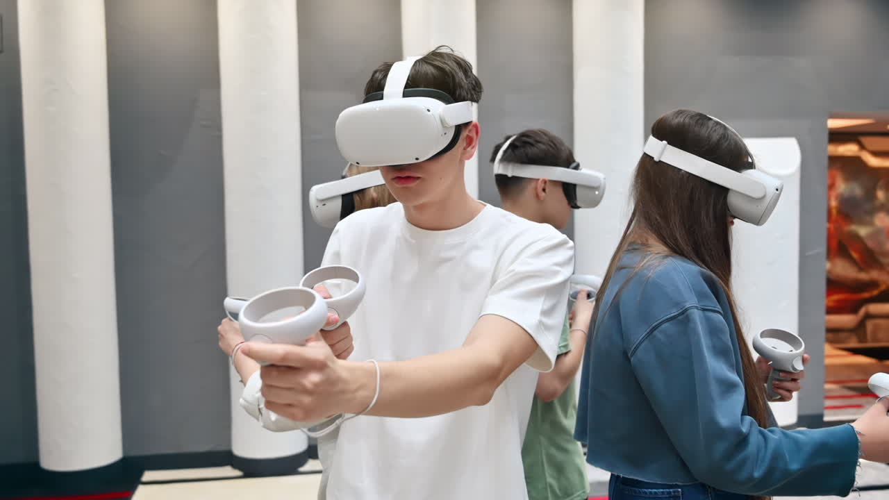 Quattro adolescenti con visori VR e controller che giocano in team in un'arena VR. Rallentatore
