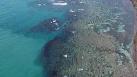 panoramic aerial overview of shallow shoreline fringing reefs with ocean waves crashing during daytime - catanduanes, philippines