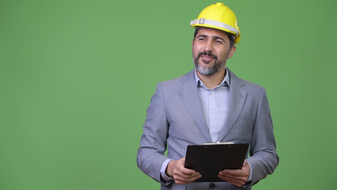 Handsome Persian bearded businessman as engineer directing with clipboard