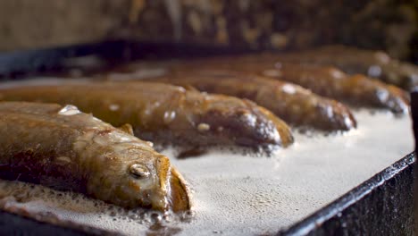 Close-up-on-fish-trout-head-being-grilled-in-griddle-full-of-hot-oil-to-get-golden-brown