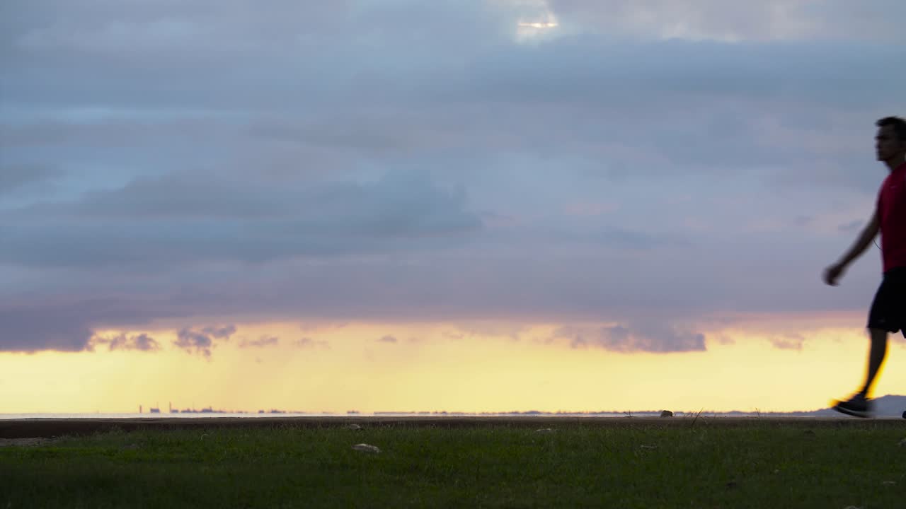하와이 호놀룰루 알라모아나 해변 공원에서 일몰 장면을 바라보며 프레임 속을 걷는 남자