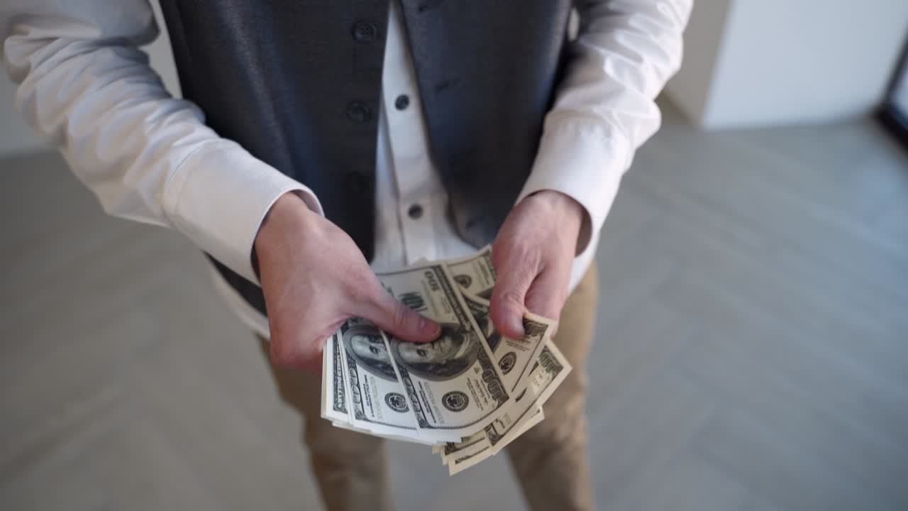 젊은 직원이 직장에서 급여를 받은 후 돈을 세고 있습니다.