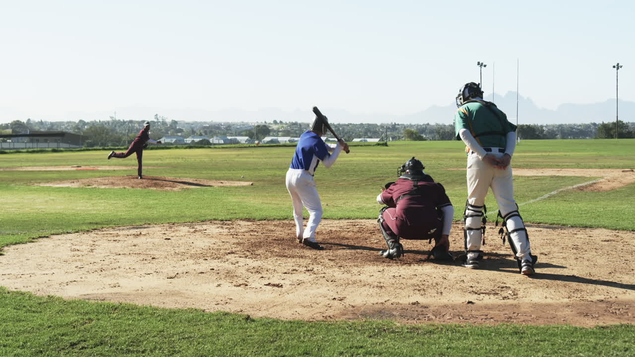 Multiracial male players and umpire playing baseball on a pitch, slow motion