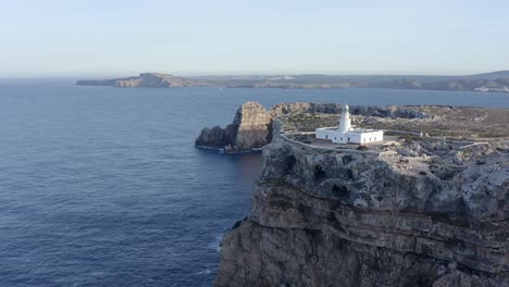 huge clifftops on the island of menorca show the scale of cavalleria lighthouse